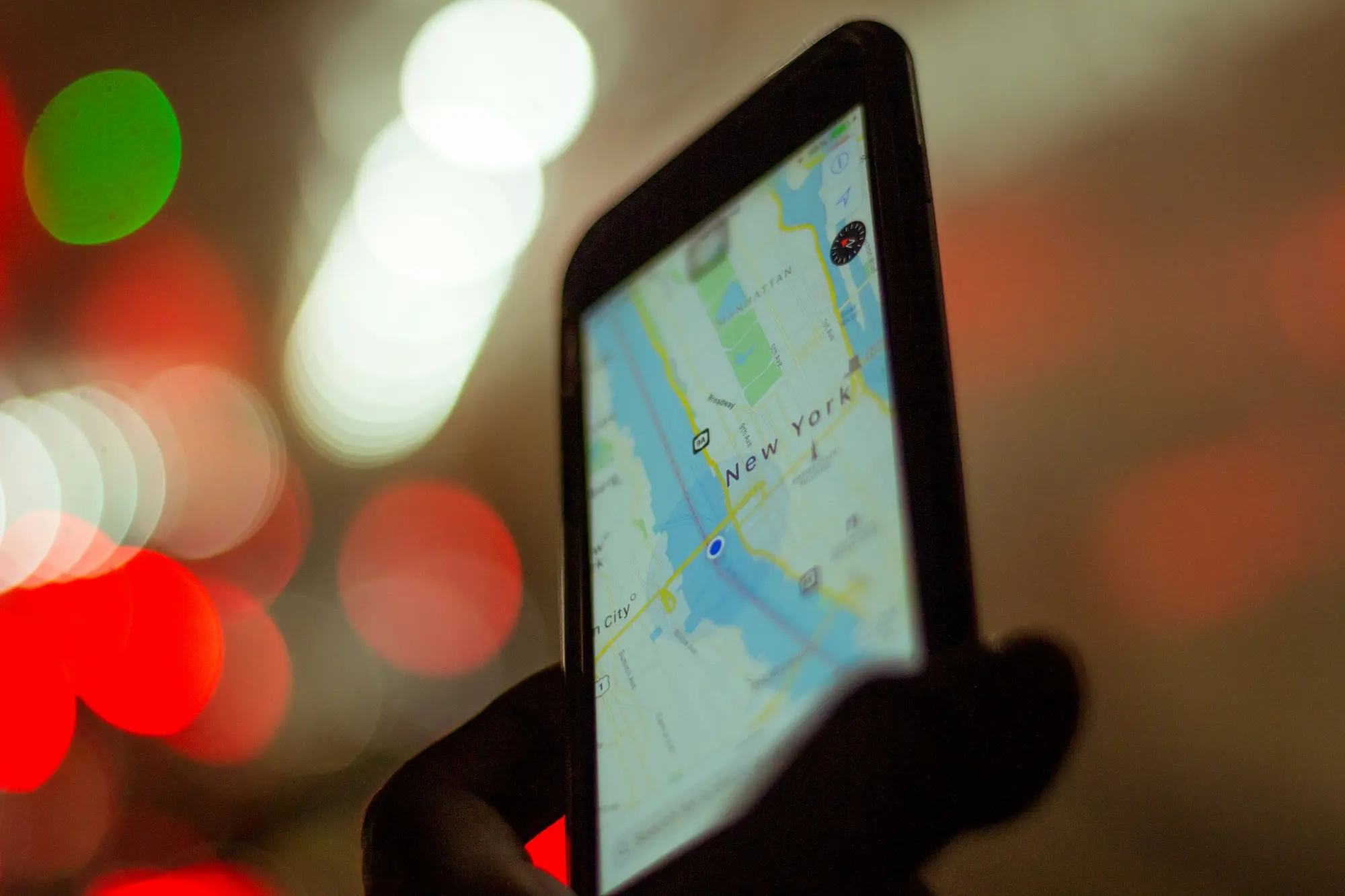 Traveler holding a smartphone showing a map while standing on a cobblestone street in a European city