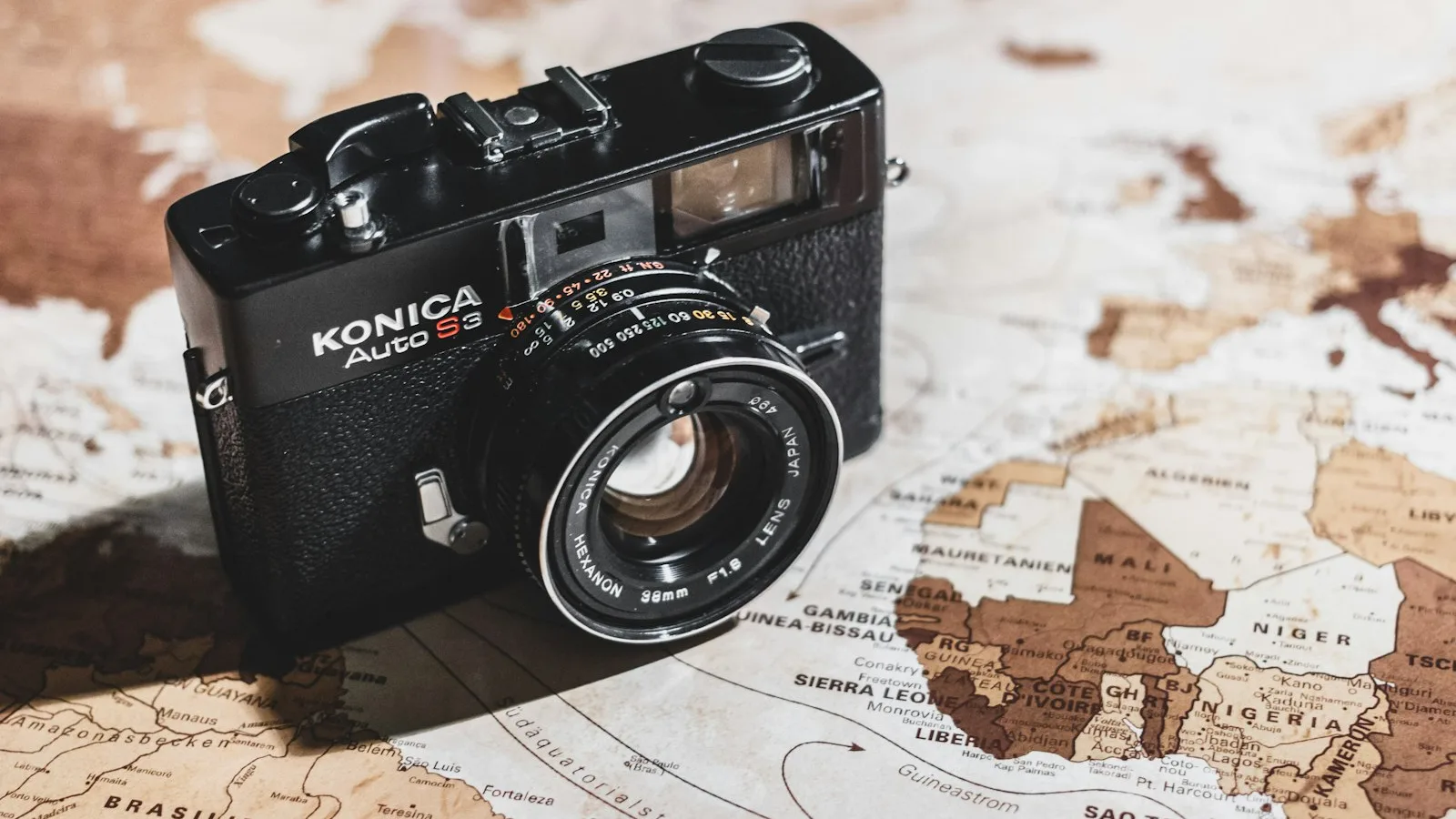A compact film-style travel camera sitting on a world map